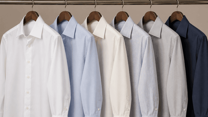 Six dress shirts on hangers with their collars pressed and standing